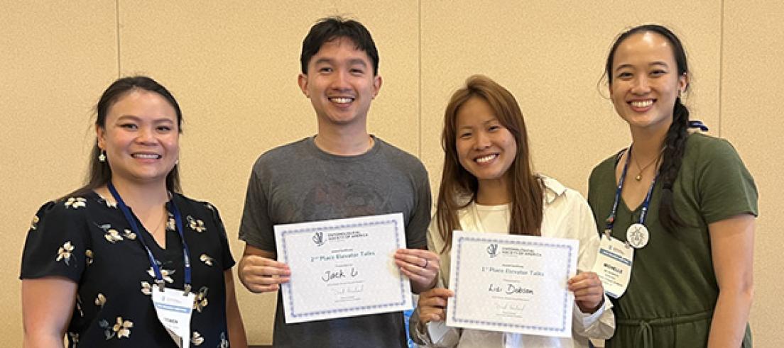 Four people holding certificate awards.